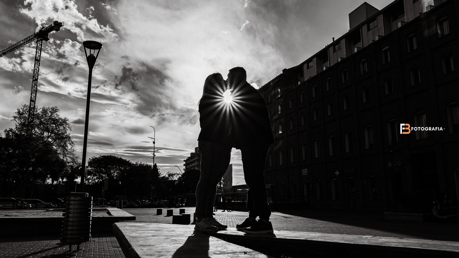 Pareja besándose a contraluz en Rosario, con el sol entre sus siluetas